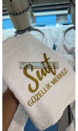 Nakış makinesinde beyaz havlu üzerine gold güzellik merkezi logo nakışı